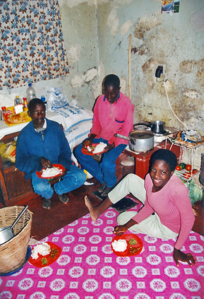 2001, Musole, Kabwe, Zambia, drie jongeren eten op de grond